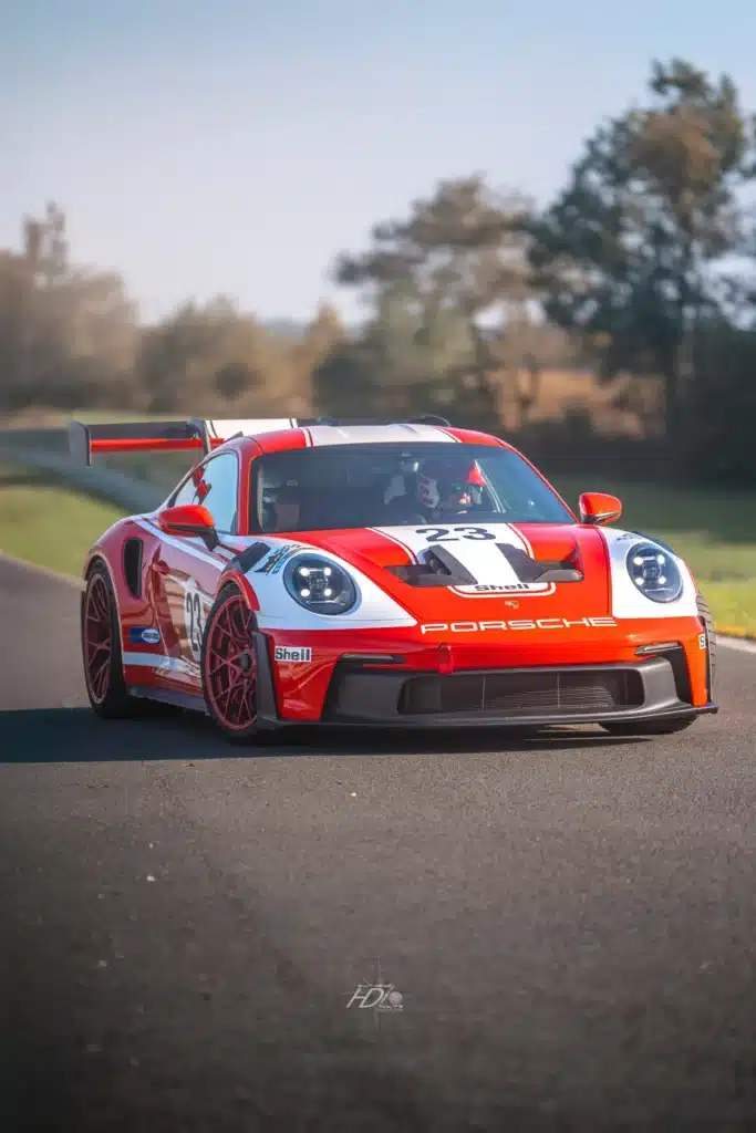 Porsche rouge numéro 23 sur circuit avec décoration Shell