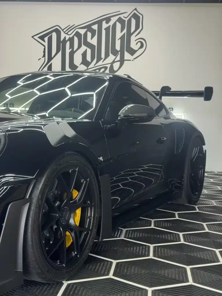 Détail d’une Porsche noire brillante avec étriers jaunes chez Prestige Cover